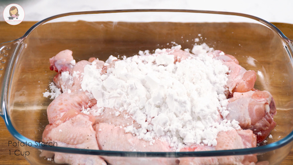 Marinated chicken wings and corn starch in a mixing bowl.