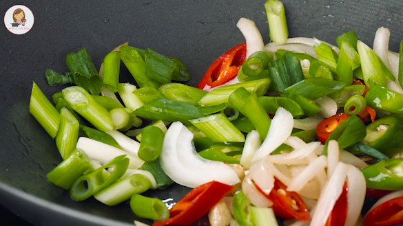 A black wok containing stir fry vegetables. 