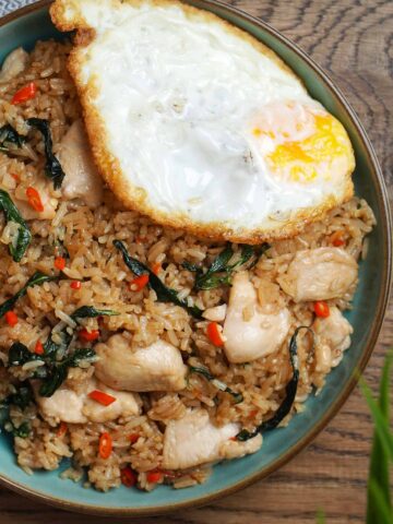 A blue colour with Basil Fried Rice with Thai style fried egg on top of it.