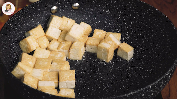 An image of stir fried tofu cubes in a large wok.