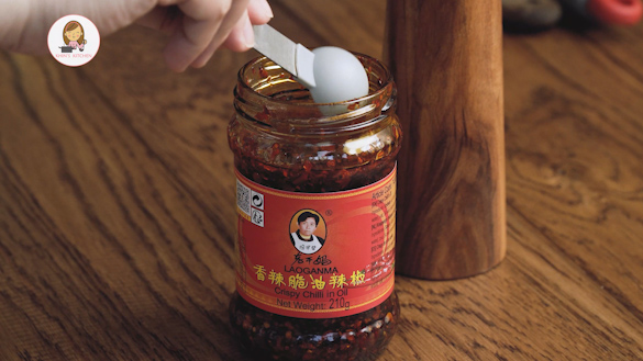 A jar of chilli oil displayed on the wooden table.