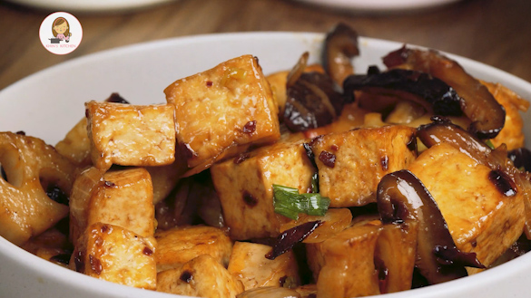 A white bowl containing stir fried tofu with vegetables and chilli flakes.