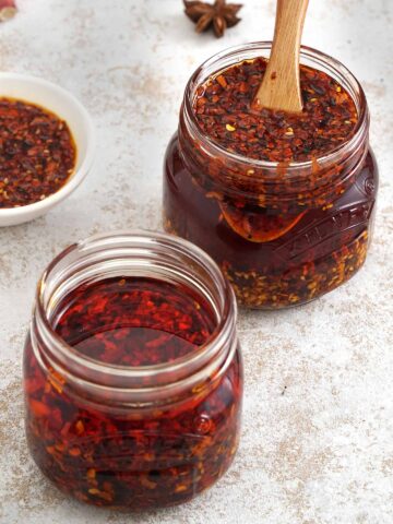 Two jars of chilli oil with small wooden spoon.