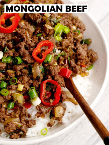 ground mongolian beef on top of the rice in the white bowl with wooden spoon.