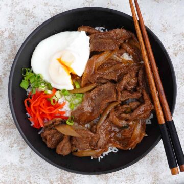 japanese stir fry beef on the white rice with a side of poached egg and spring onions