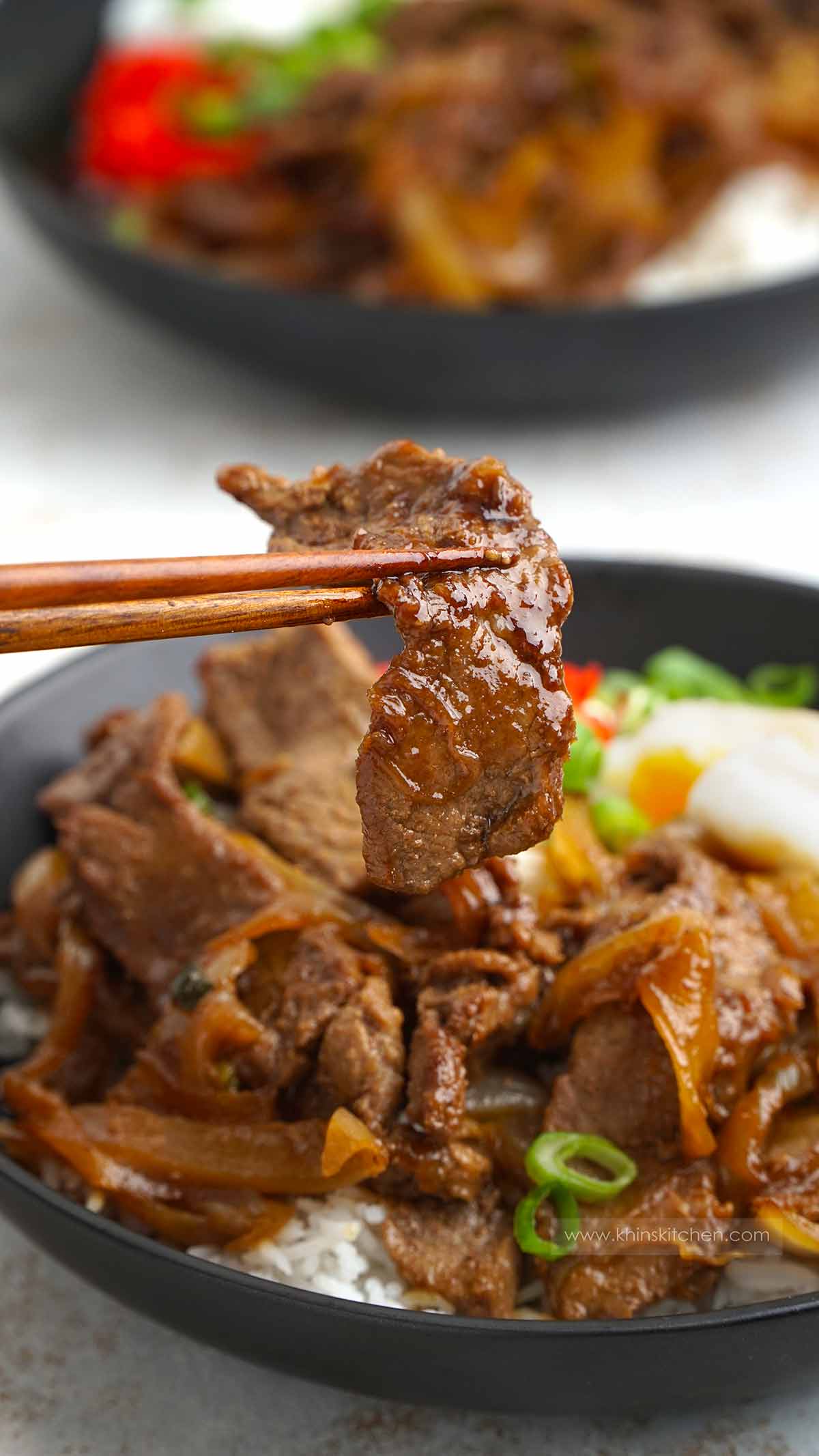 Wooden chop stick holding stir fried japanese beef.