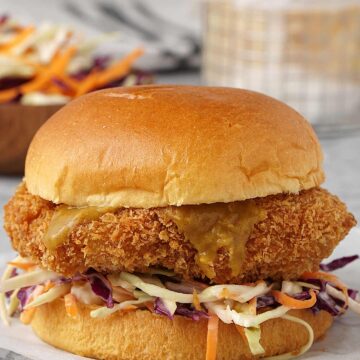 japanese style chicken burger in the foreground and chips in a basket in the background.