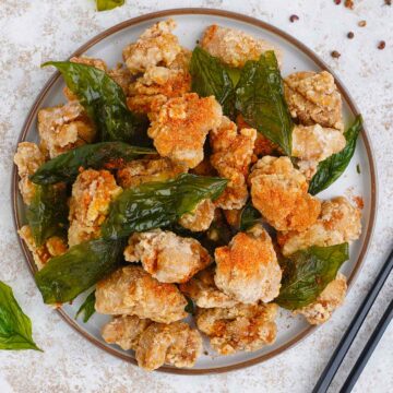 a plate full of thaiwanese style chicken pop corn with black color chop stick on the side