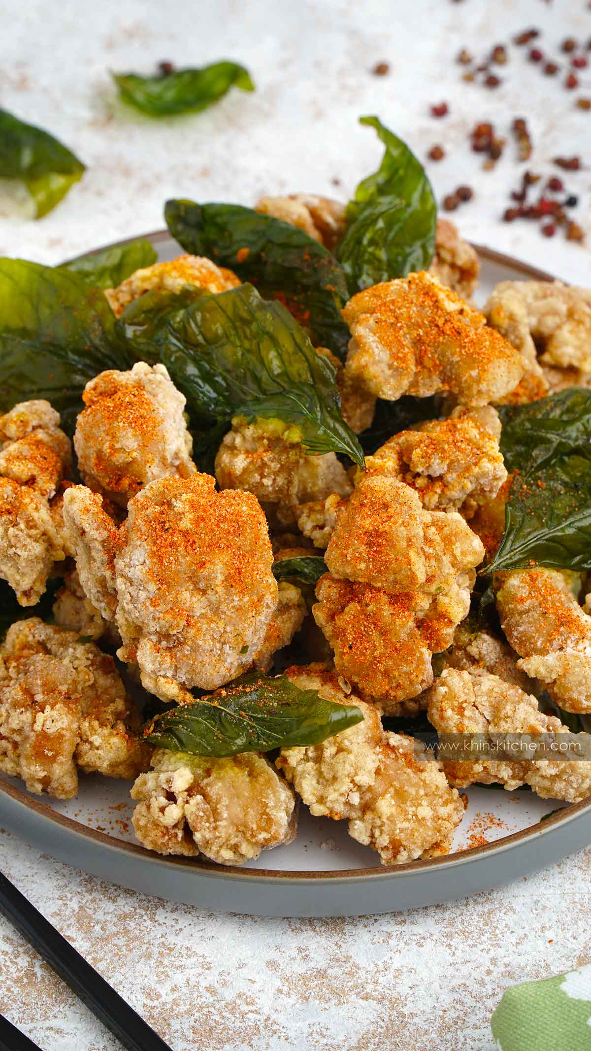 A close up shot of grey plate filled with Taiwanese fried chicken and basil leaves.