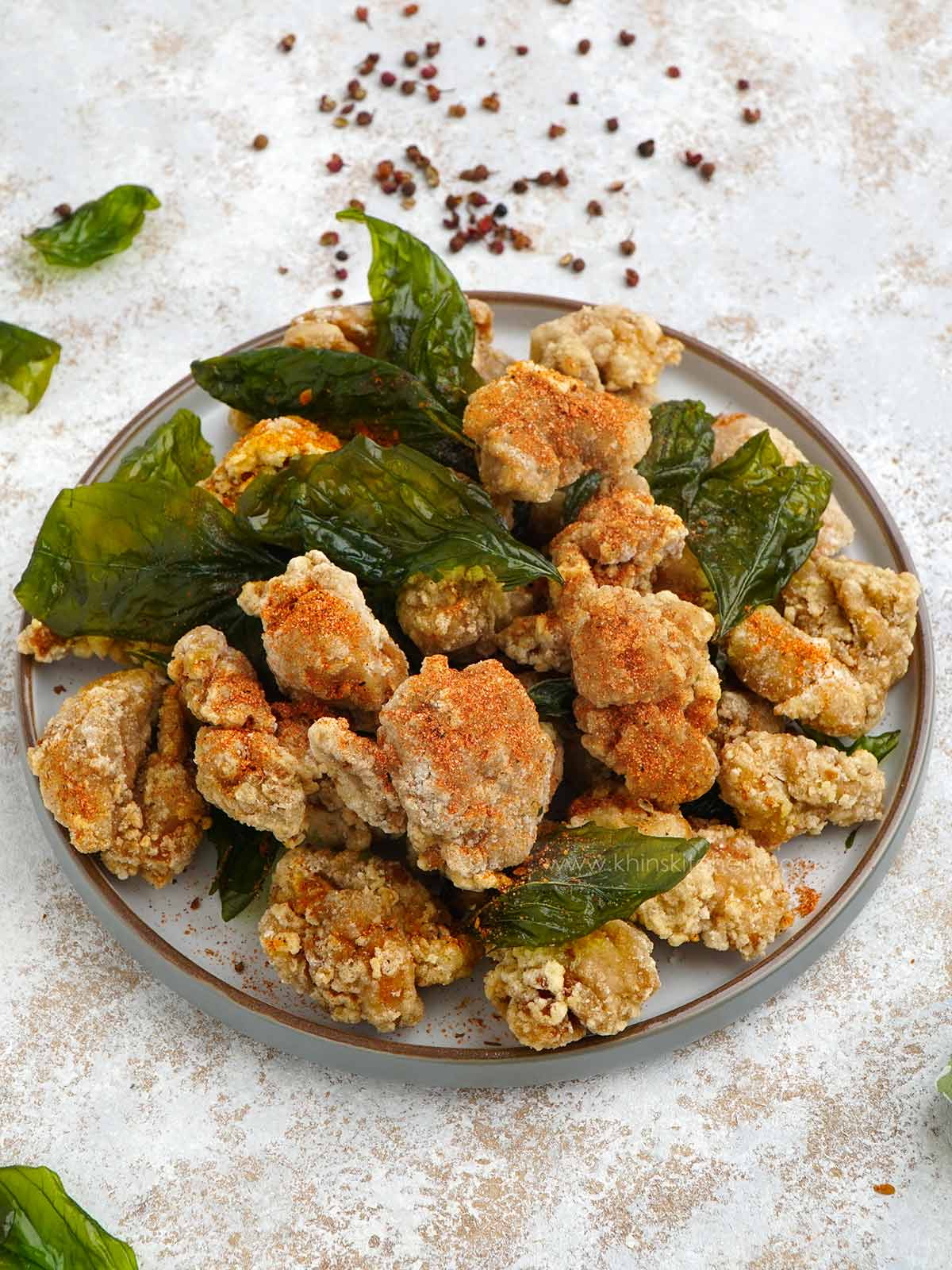 Taiwanese popcorn chicken with basil leaves in the grey plate.