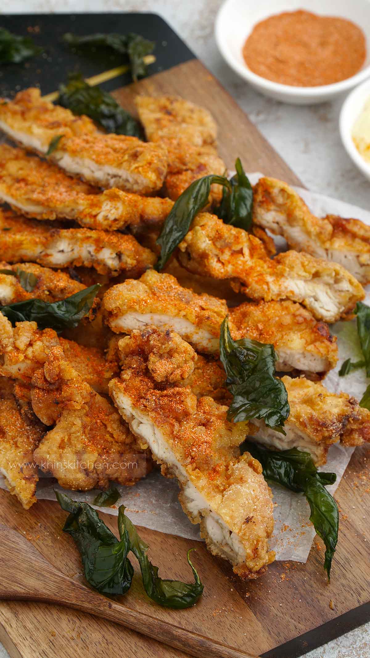 sliced fried chicken and crispy fried basil on the serving tray.