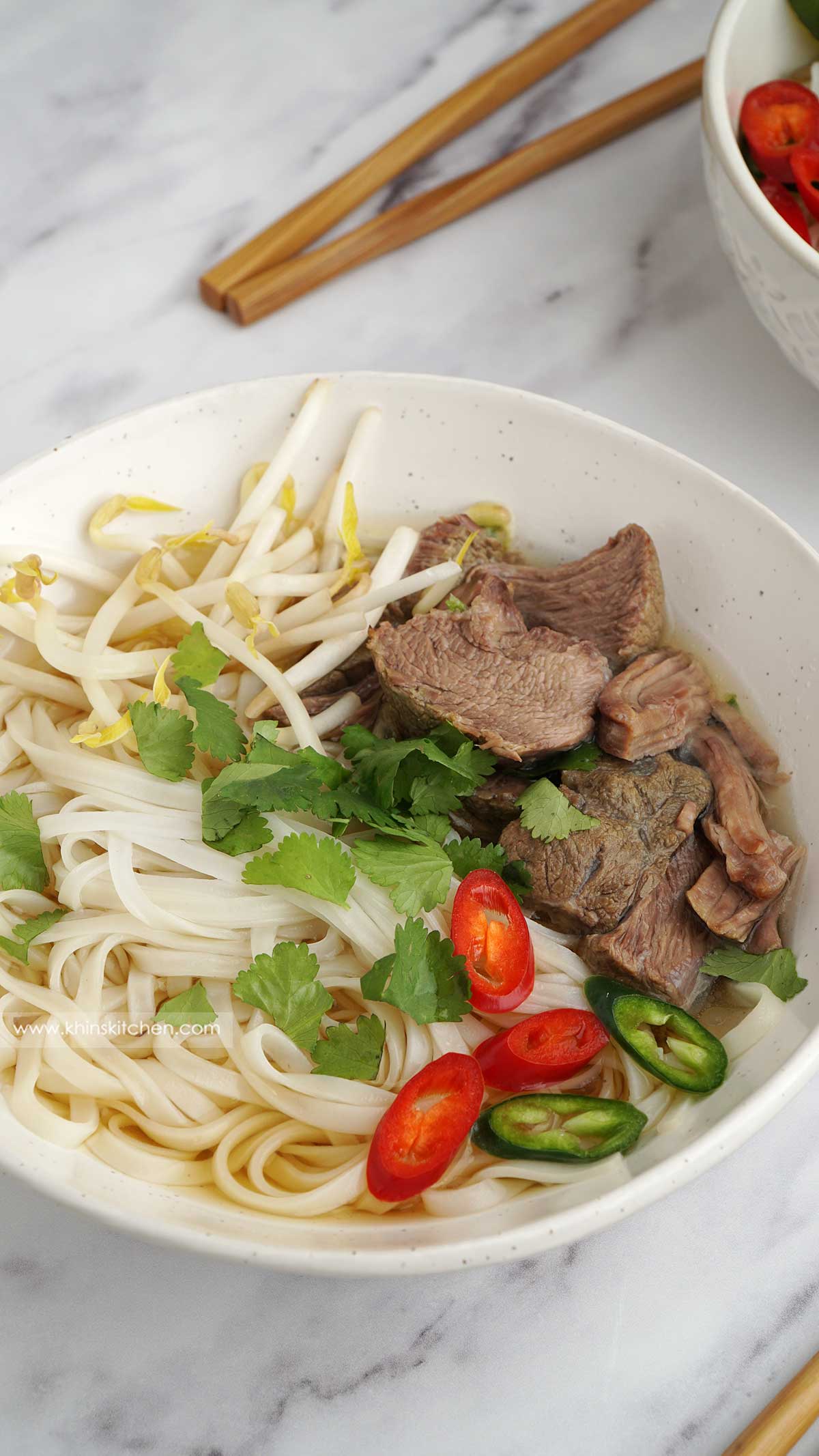 close up view of beef noodles soup in the white bowl.