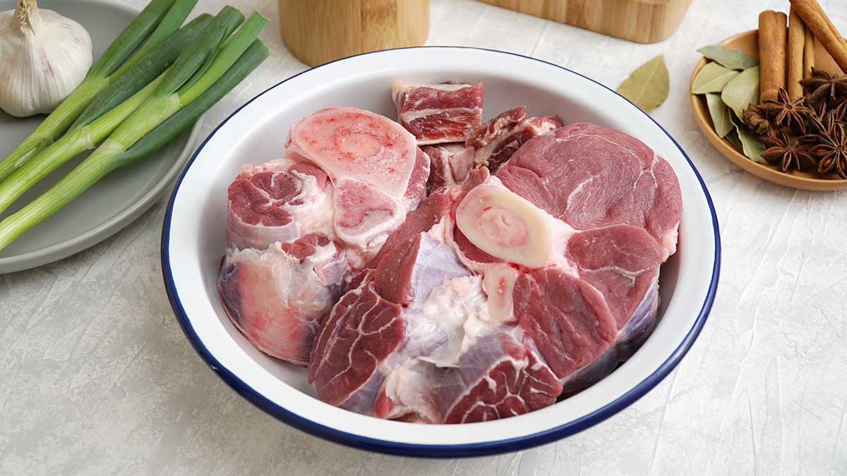 beef shanks in the white bowl and spices in the wooden small plate.