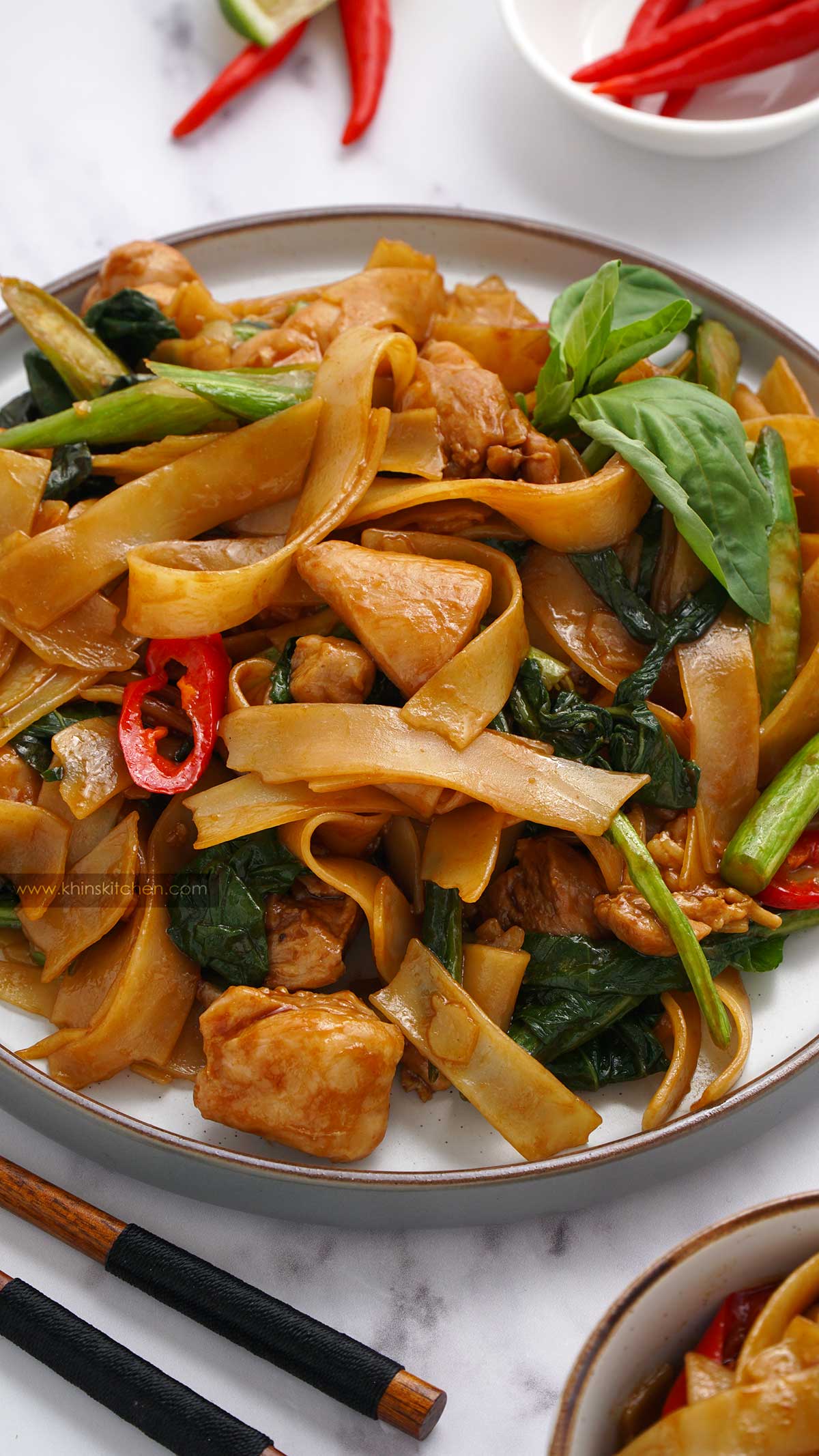 Close up view of thai noodles in a white plate with wooden chop stick.