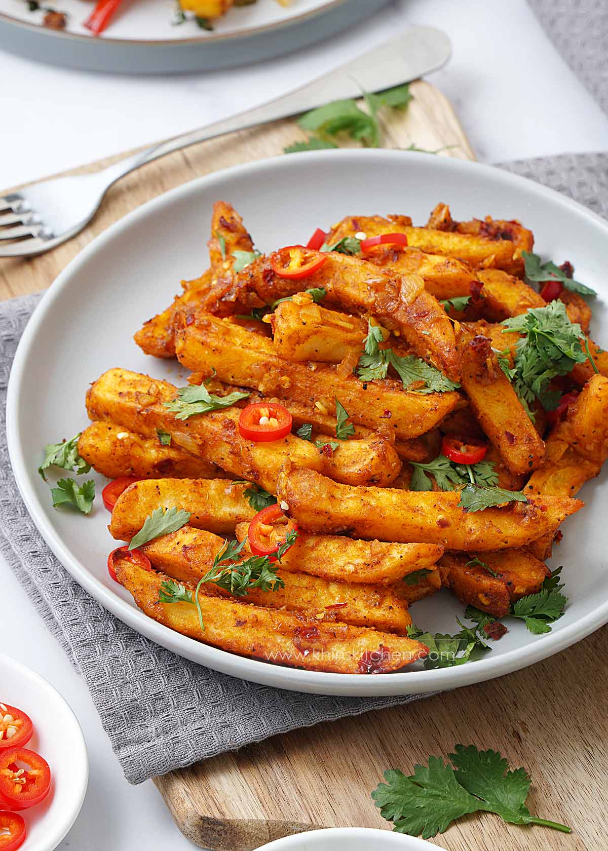 Close up shot of golden masala fries with vegetables in a grey plate. 