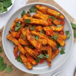 A grey bowl containing spicy fried chips topped with sliced chilli and coriander.