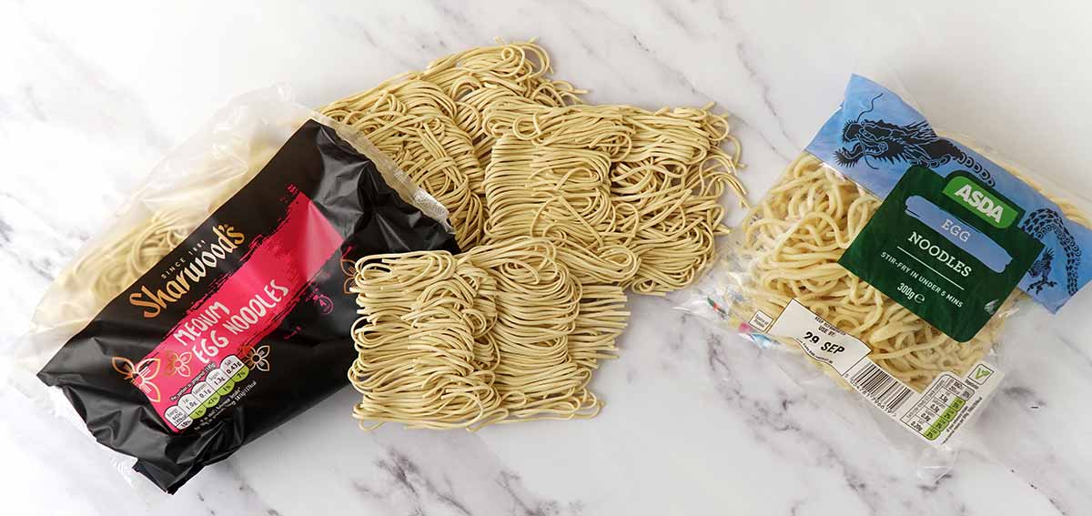 Dried egg noodles and fresh egg noodles displayed on the white table. 