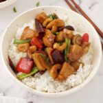 A white bowl containing spicy chicken stir fries, mushrooms, chillies and cashew nuts.