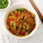 A white bowl containing stir fry cellophane noodles with vegetables.