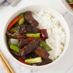 A white bowl containing, stir fry beef and vegetables.