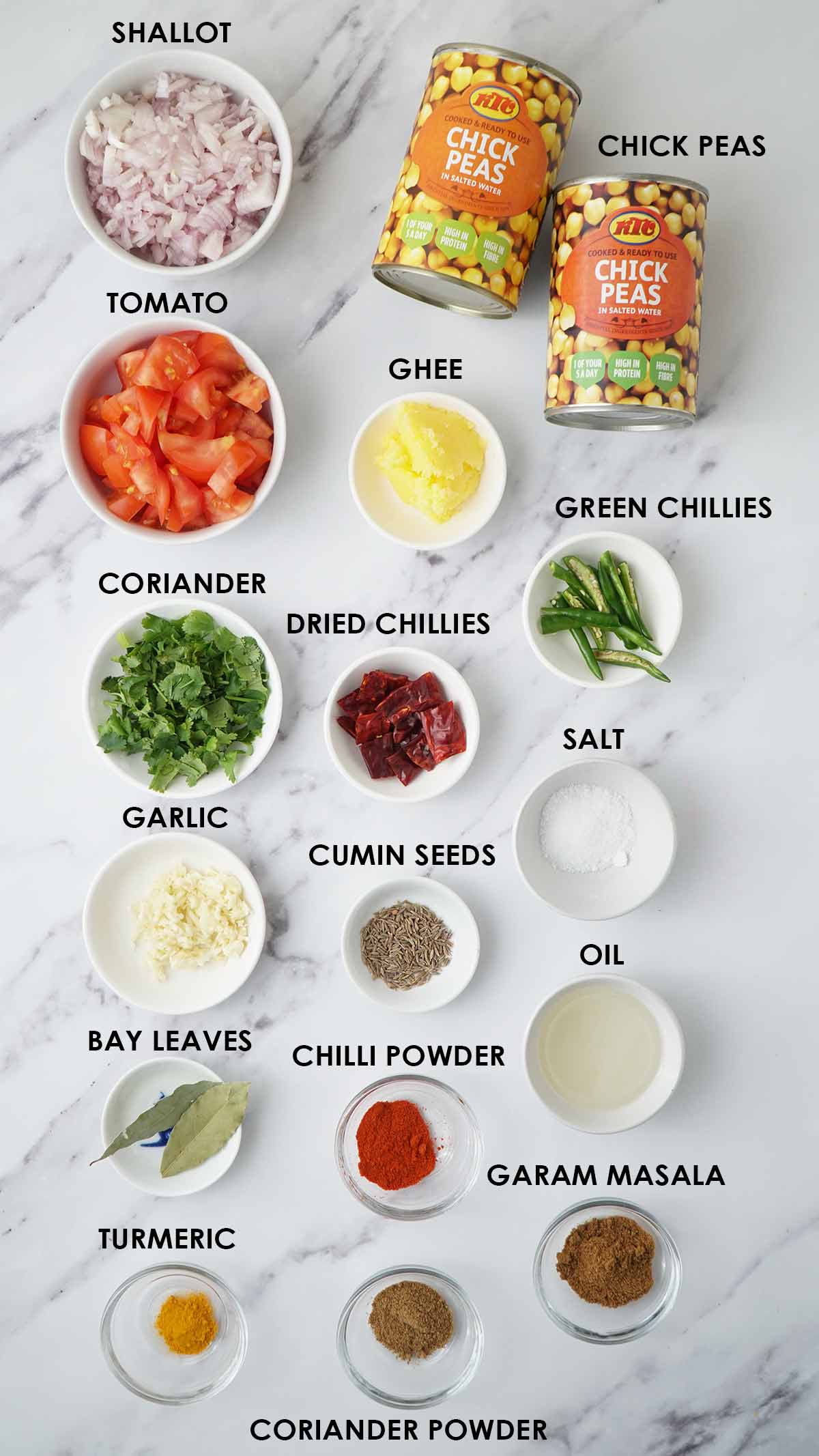 Labelled ingredients of making chickpea curry displayed on the white table. 