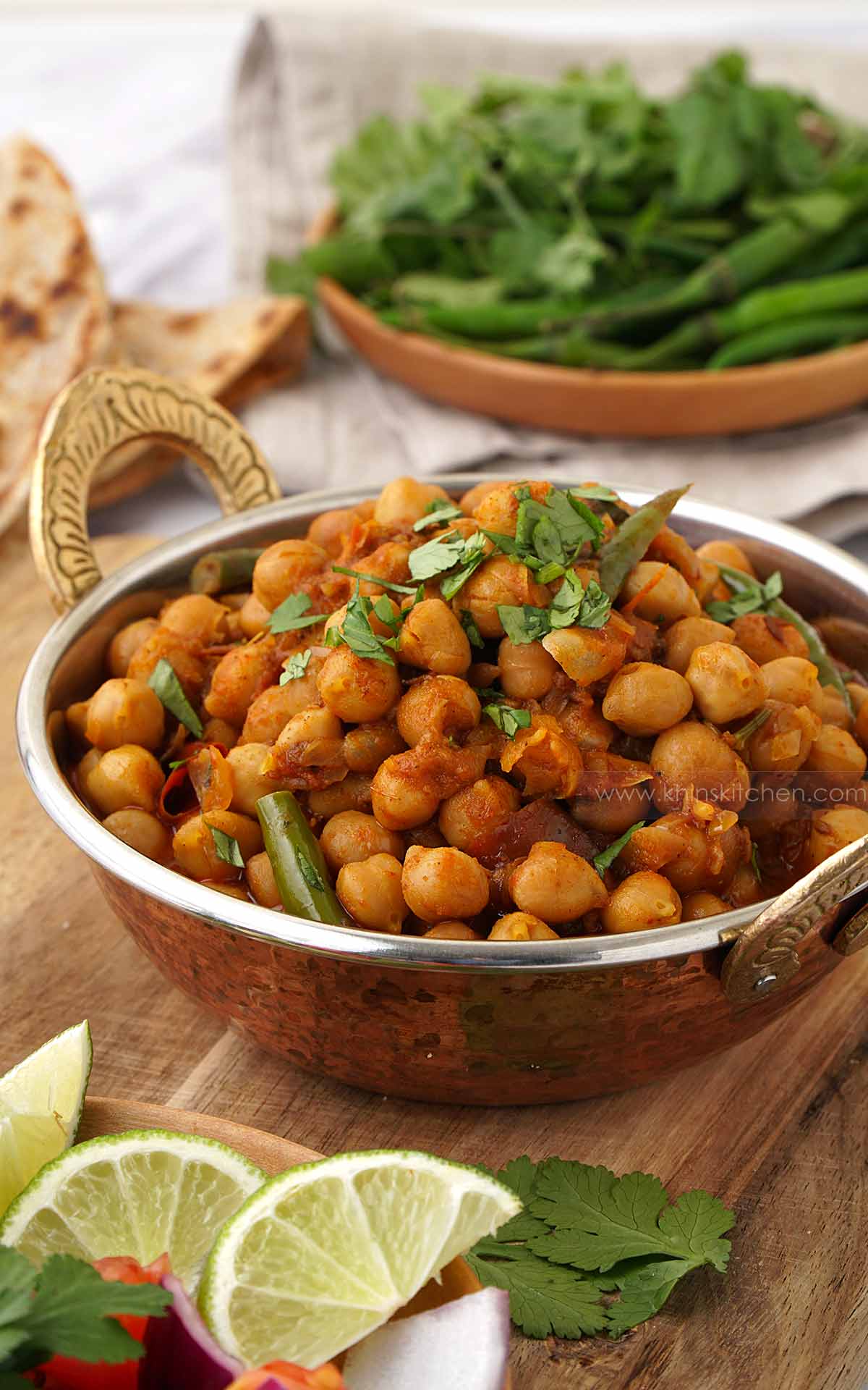 A steel metal bowl with handle containing, Indian chickpea bhaji curry with green chilli and coriander. 