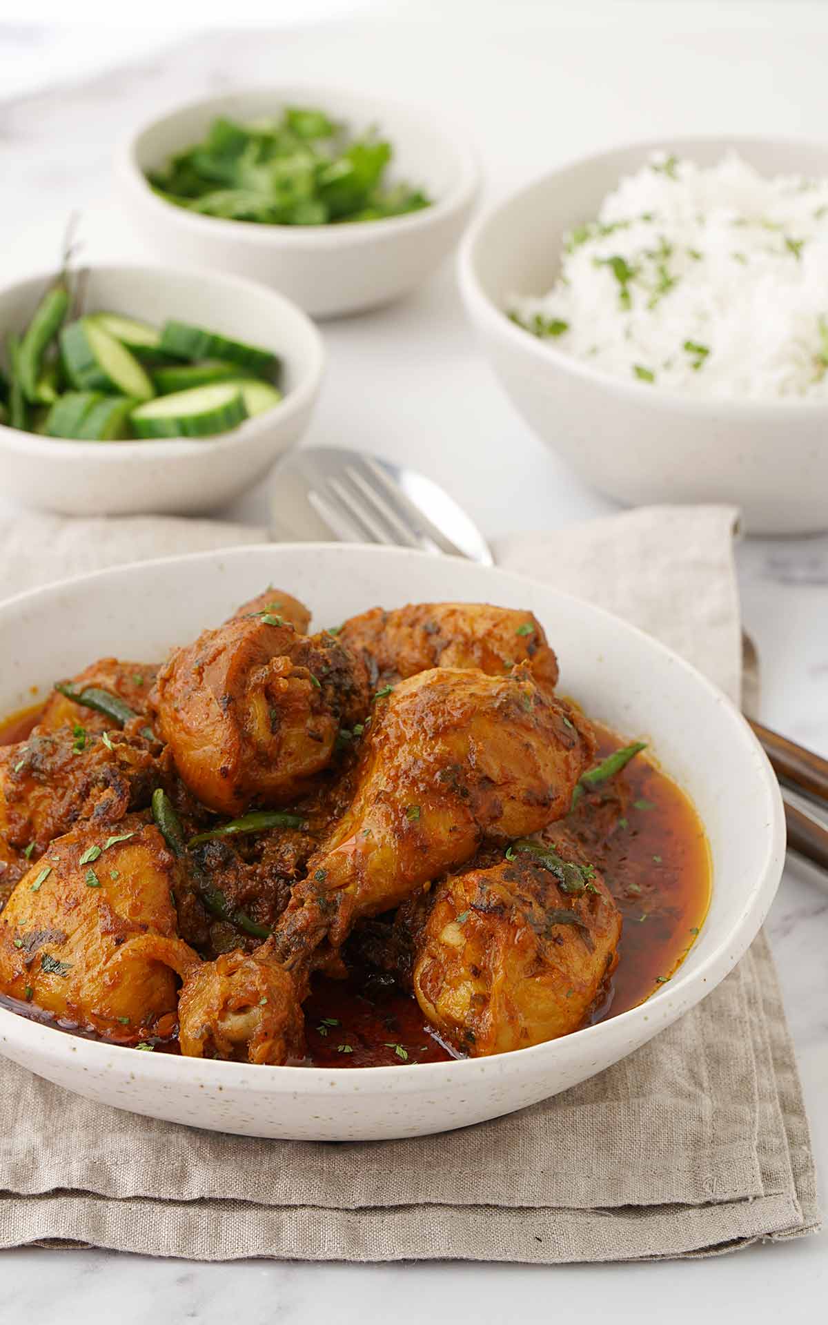 A white bowl containing chicken curry, displayed on the brown tablecloth.  