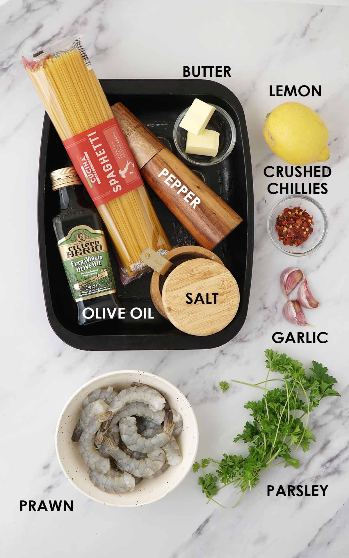 Labelled ingredients of making shrimp spaghetti displayed on the white table.
