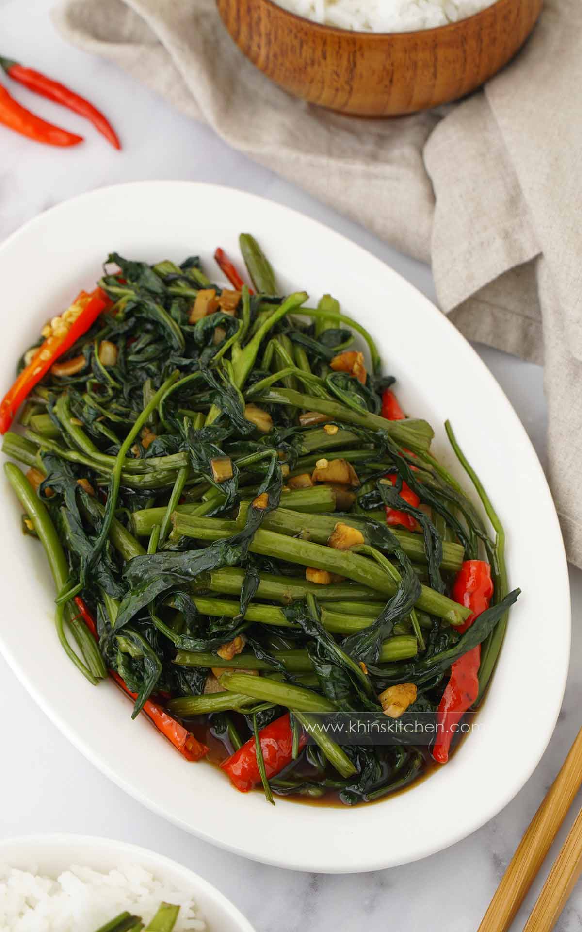A white oval plate containing Thai morning glory stir fry with garlic and chilli. 