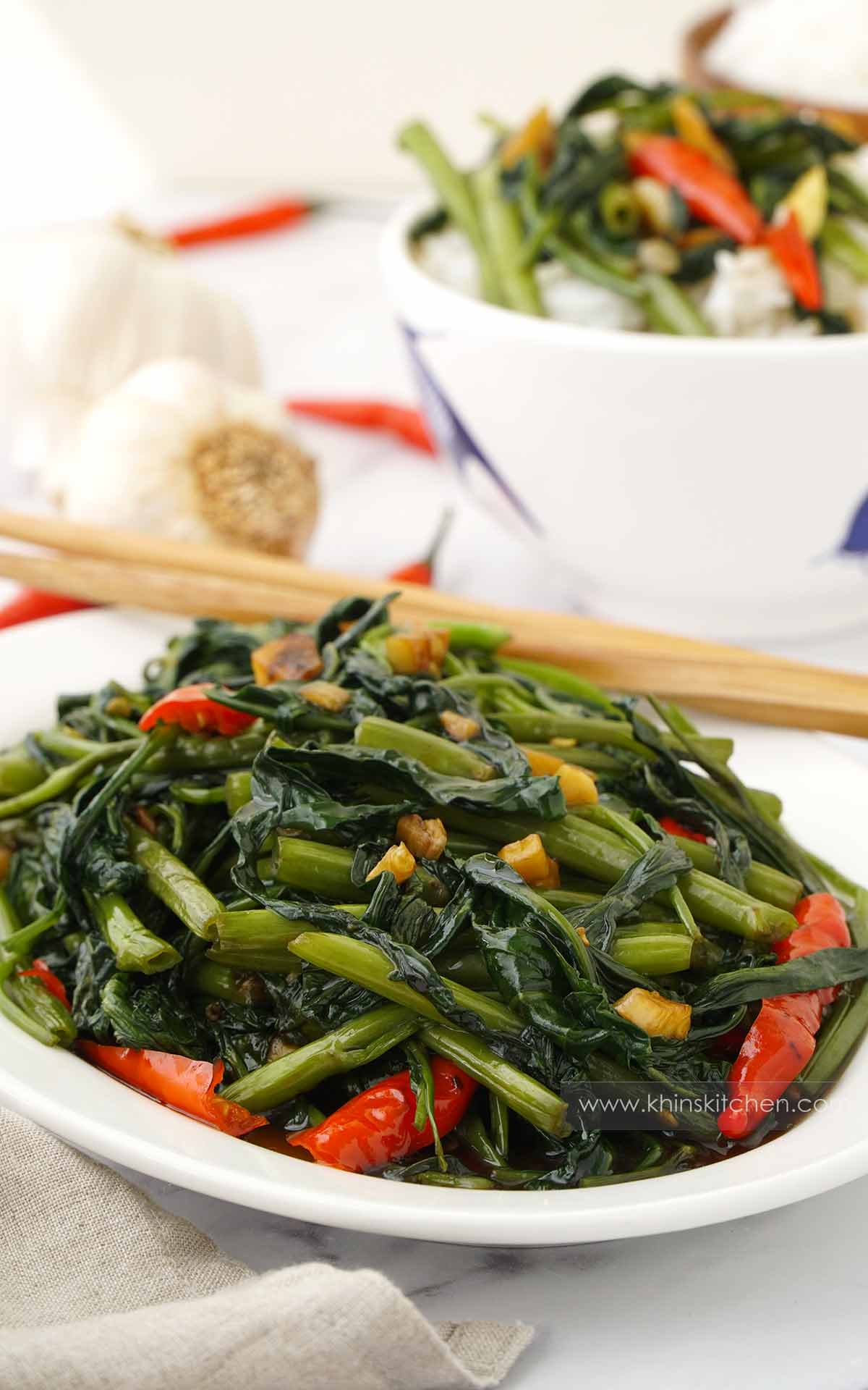 A white plate containing, stir fry morning glory with Thai red chillies and garlic. 