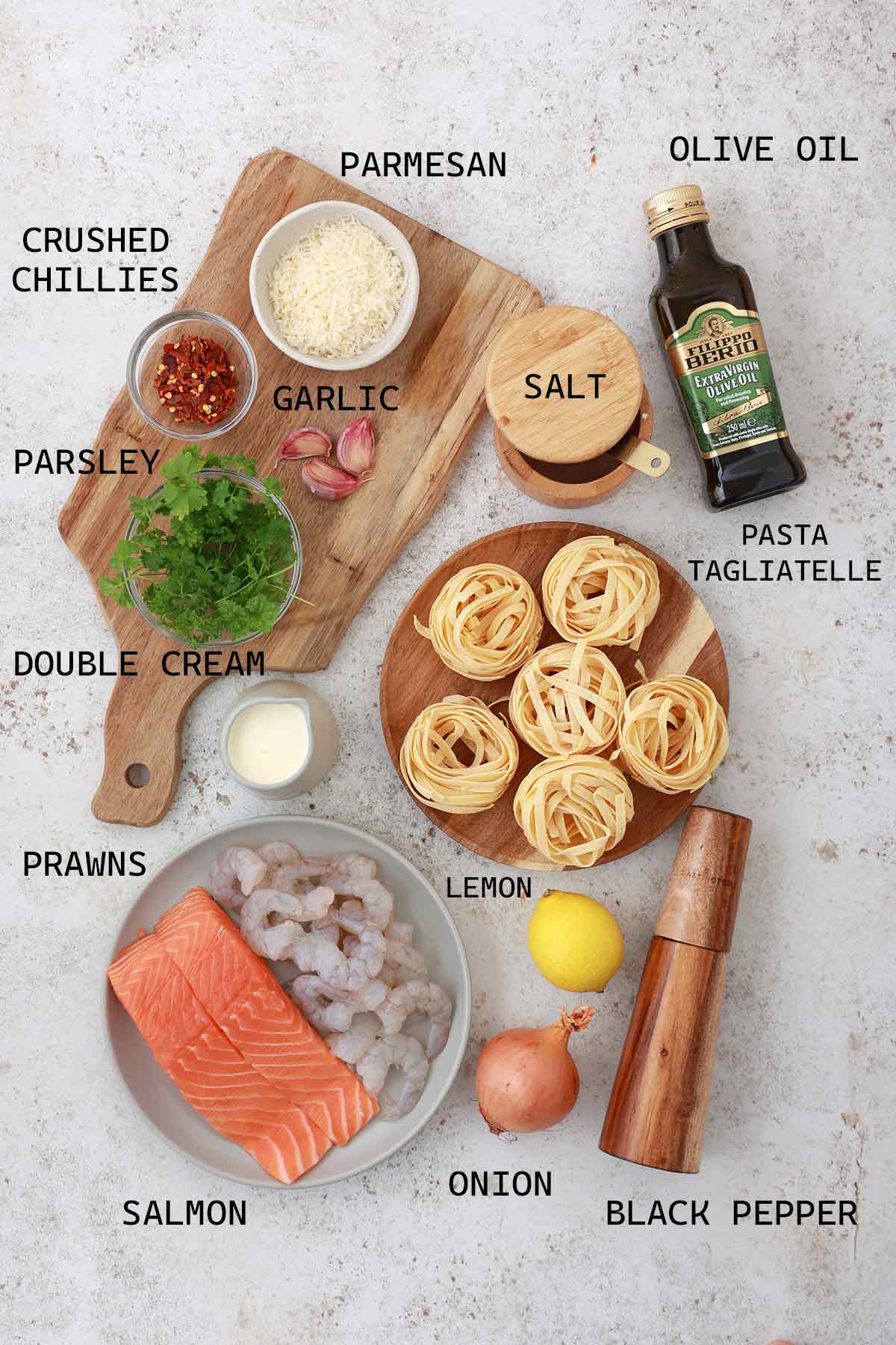 Labelled ingredients of making creamy tagliatelle with salmon and prawns.