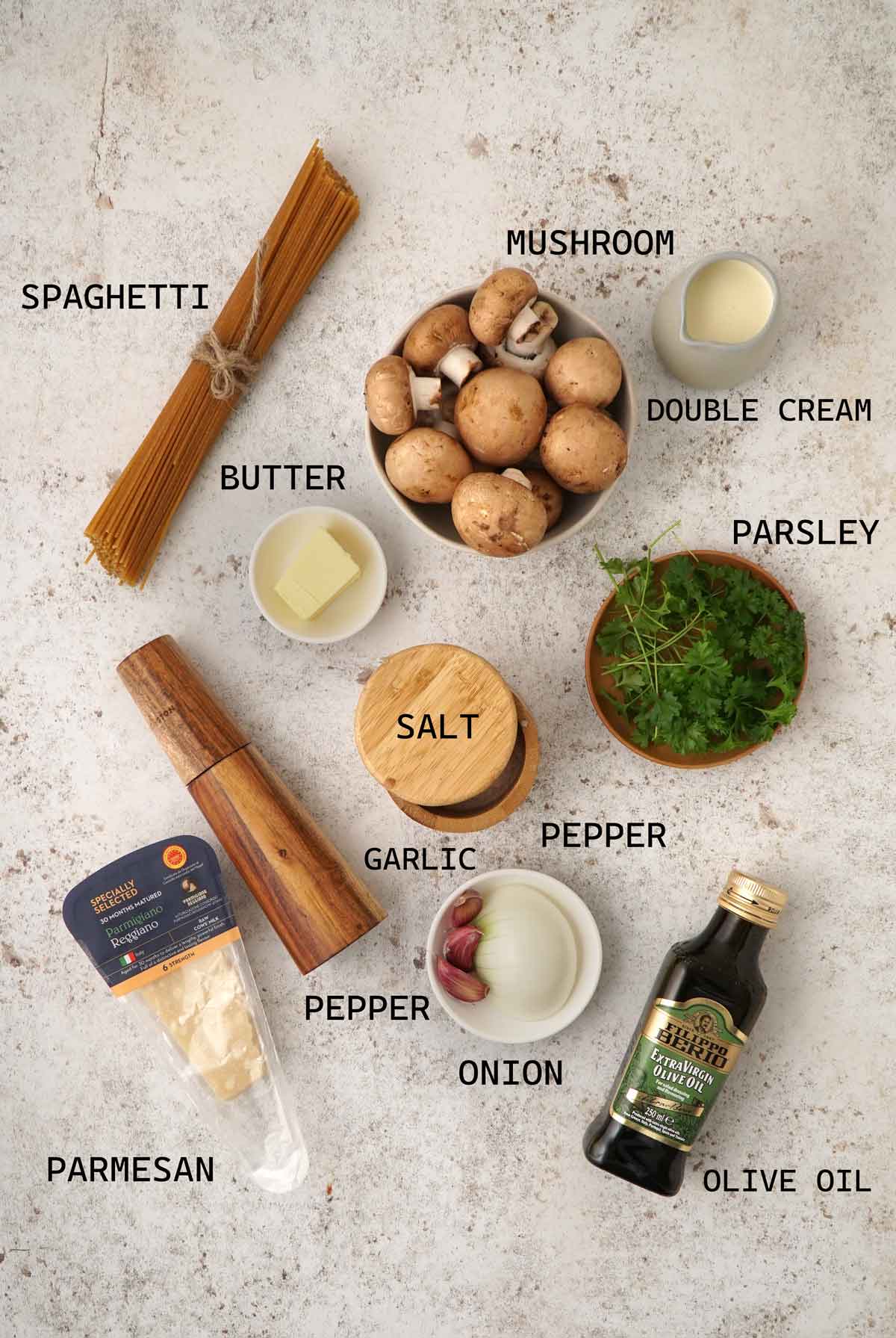 Labelled ingredients of making creamy mushroom pasta displayed on the white table. 