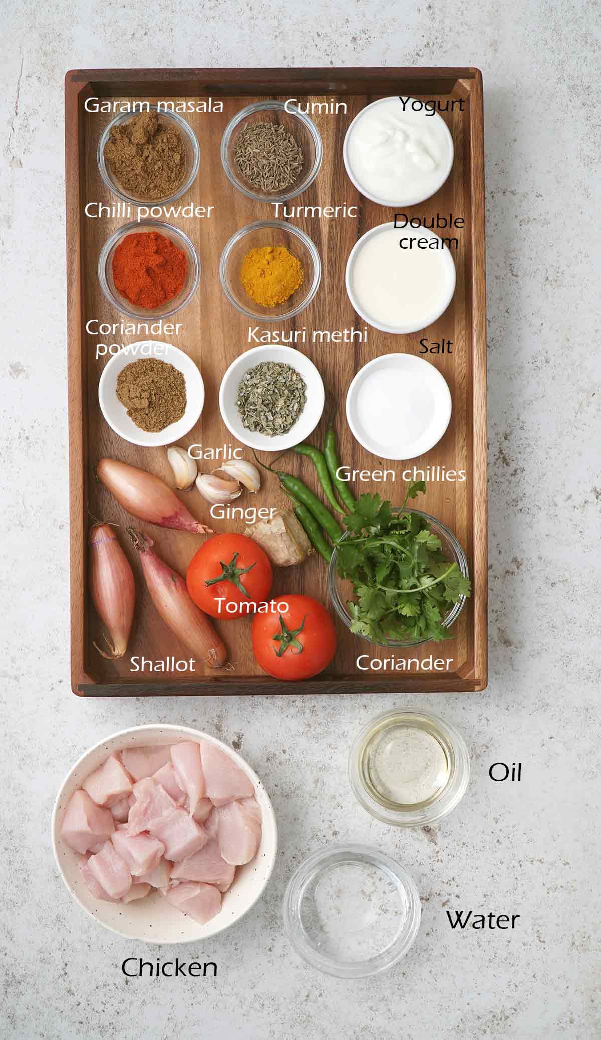 Labelled ingredients for making chicken curry displayed on the white table.