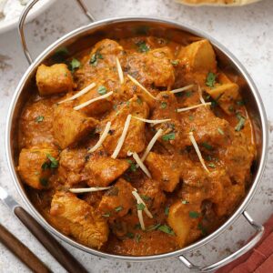 A metal bowl containing creamy Handi chicken curry.