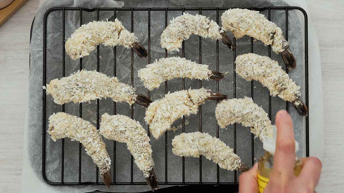 An image showing how to spray oil on the coated prawns.