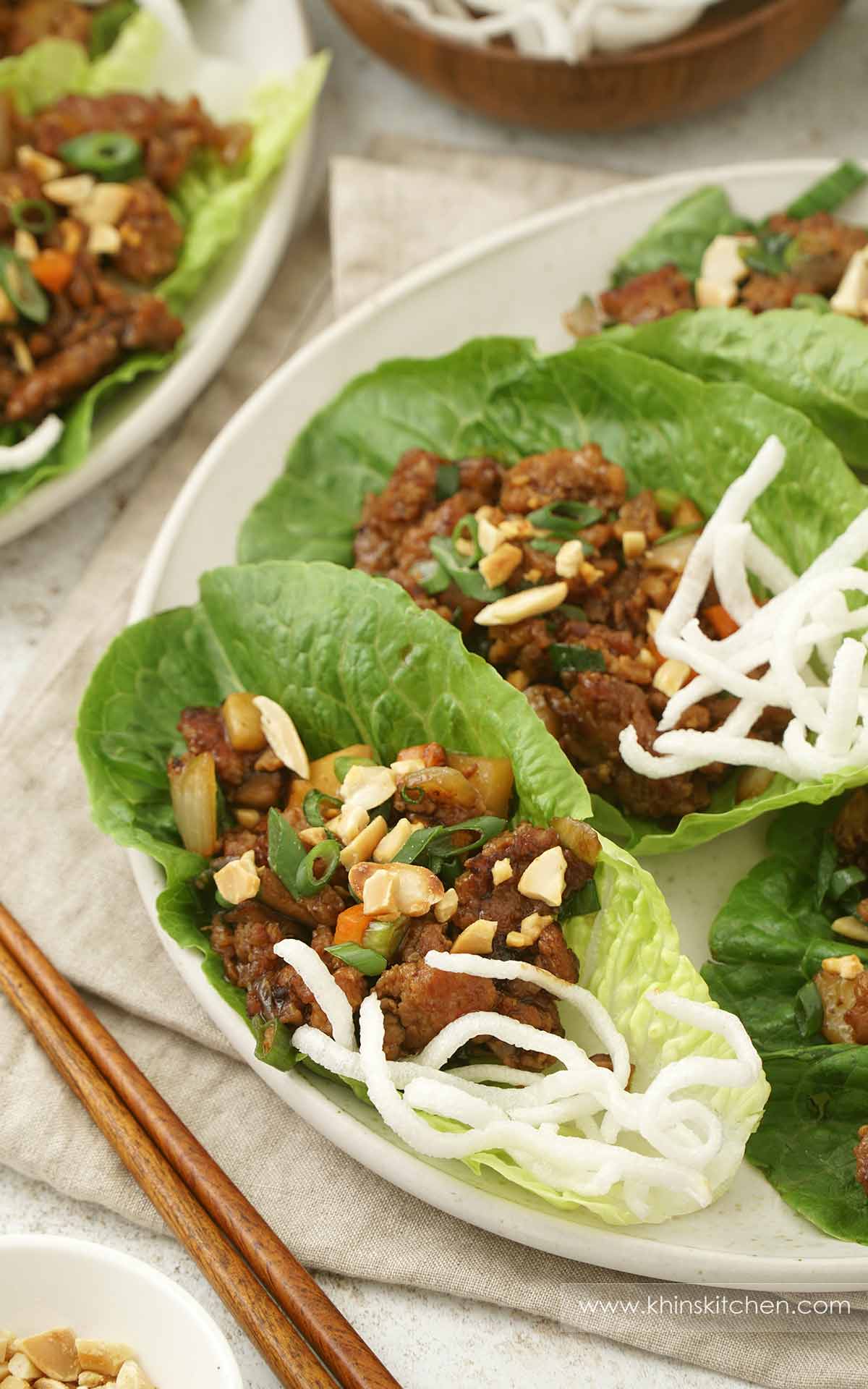 A white plate containing Chinese Yuk Sung in romaine lettuce with fried rice crisp on the side. 