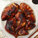 Chinese five spice roasted chicken served on the plate with dipping sauce on the side.