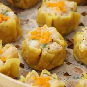 A bamboo steamer containing Chinese prawn/shrimp and chicken dim sum dumplings.