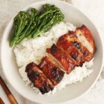A rice bowl containing Chinese char siu grilled chicken slices and steamed broccoli.