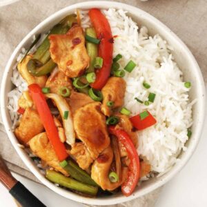 A ceramic bowl containing cooked jasmine rice and chicken stir fry with hoisin sauce.