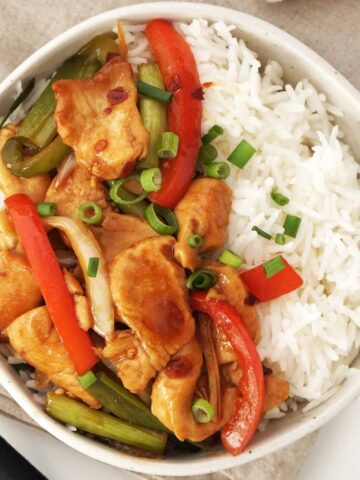 A ceramic bowl containing cooked jasmine rice and chicken stir fry with hoisin sauce.