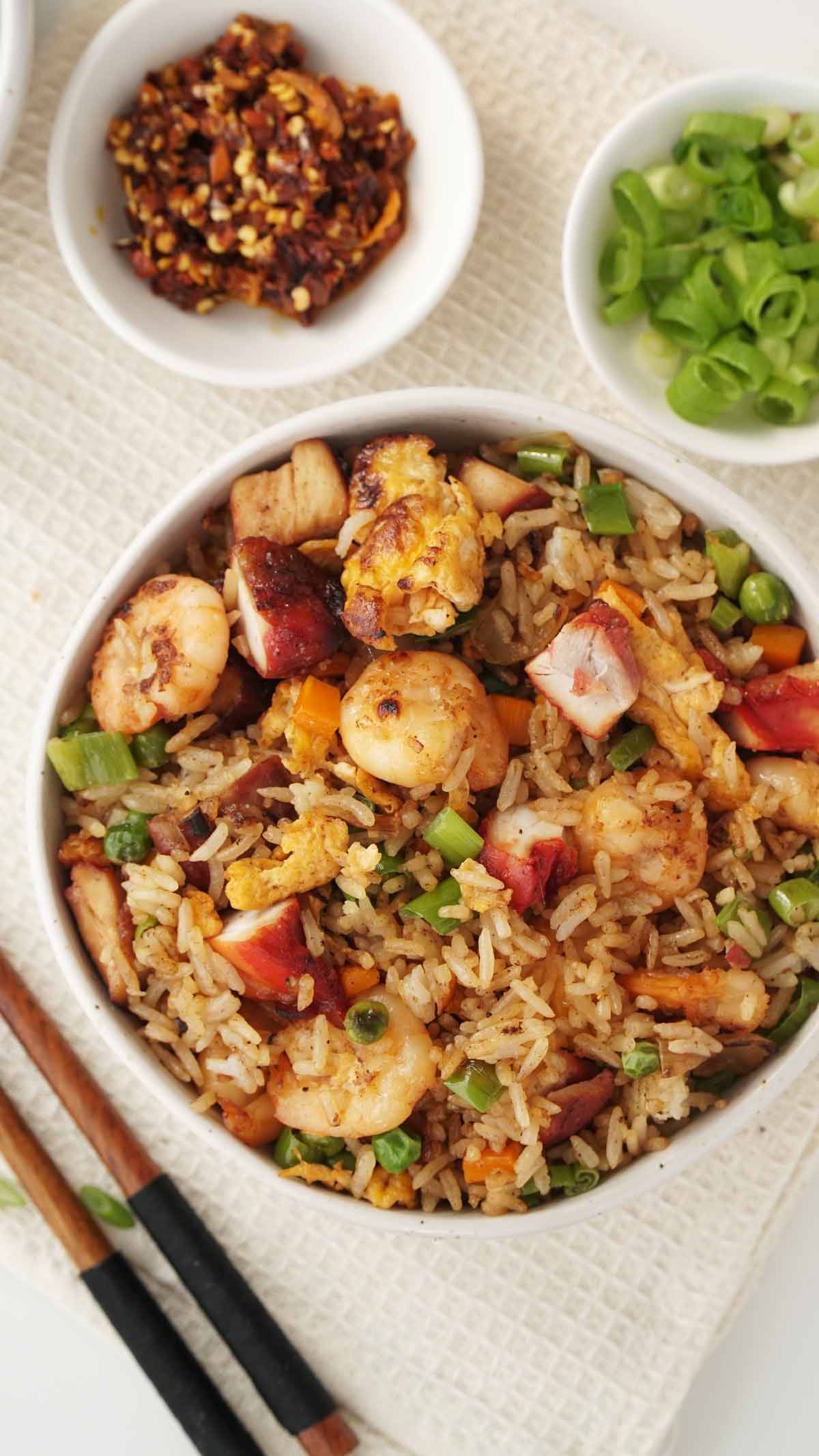 A white bowl containing fried rice with prawns, BBQ meat, and vegetables.