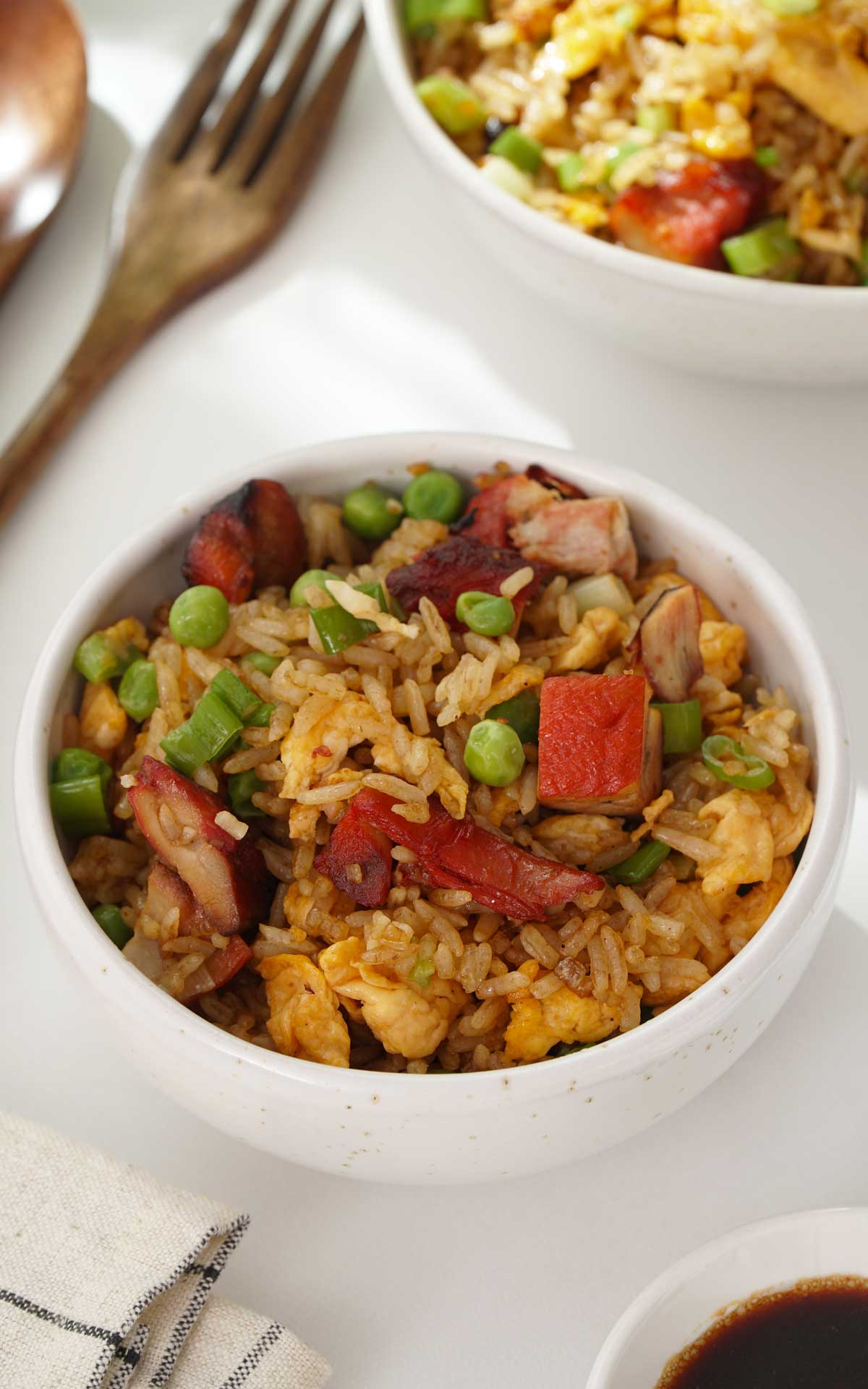A small bowl containing fried rice with egg, peas, and Chinese BBQ meat. 