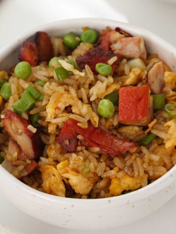 A small bowl containing, Chinese fried rice with char siu, egg, and peas.