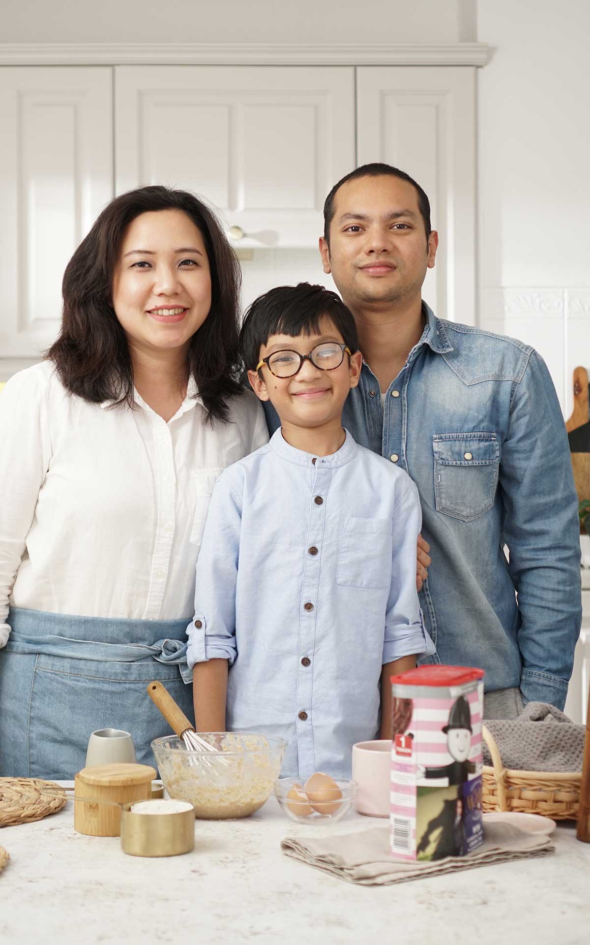 Picture of Yu Mon Khin, her husband and her son standing by the white dinning table.