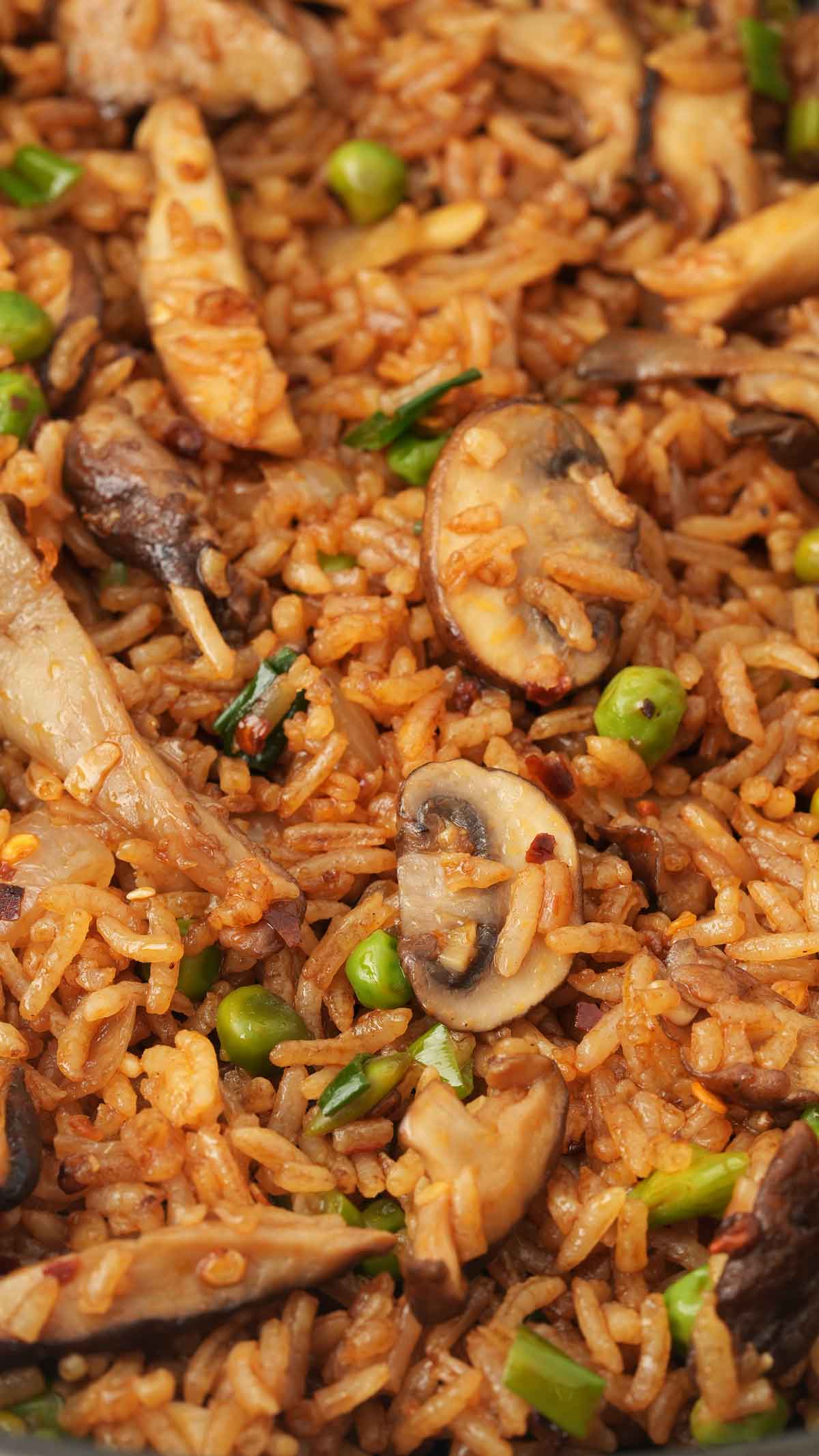A black wok containing, fried rice with mushrooms and vegetables. 