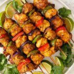 An image of 5 kebab chicken skewers on a white plate.