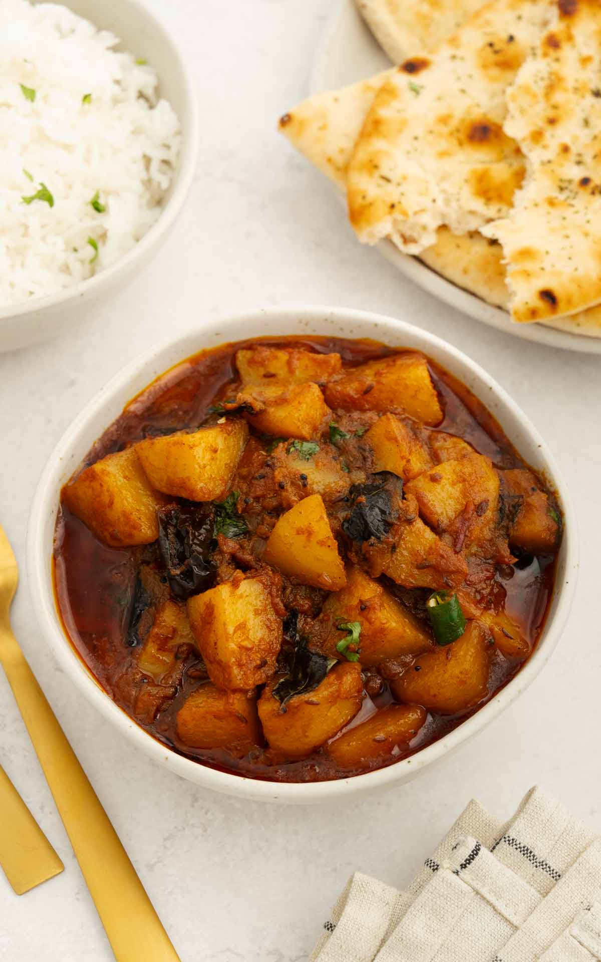 An image of potato curry in the middle , rice and naan bowl on the side. 