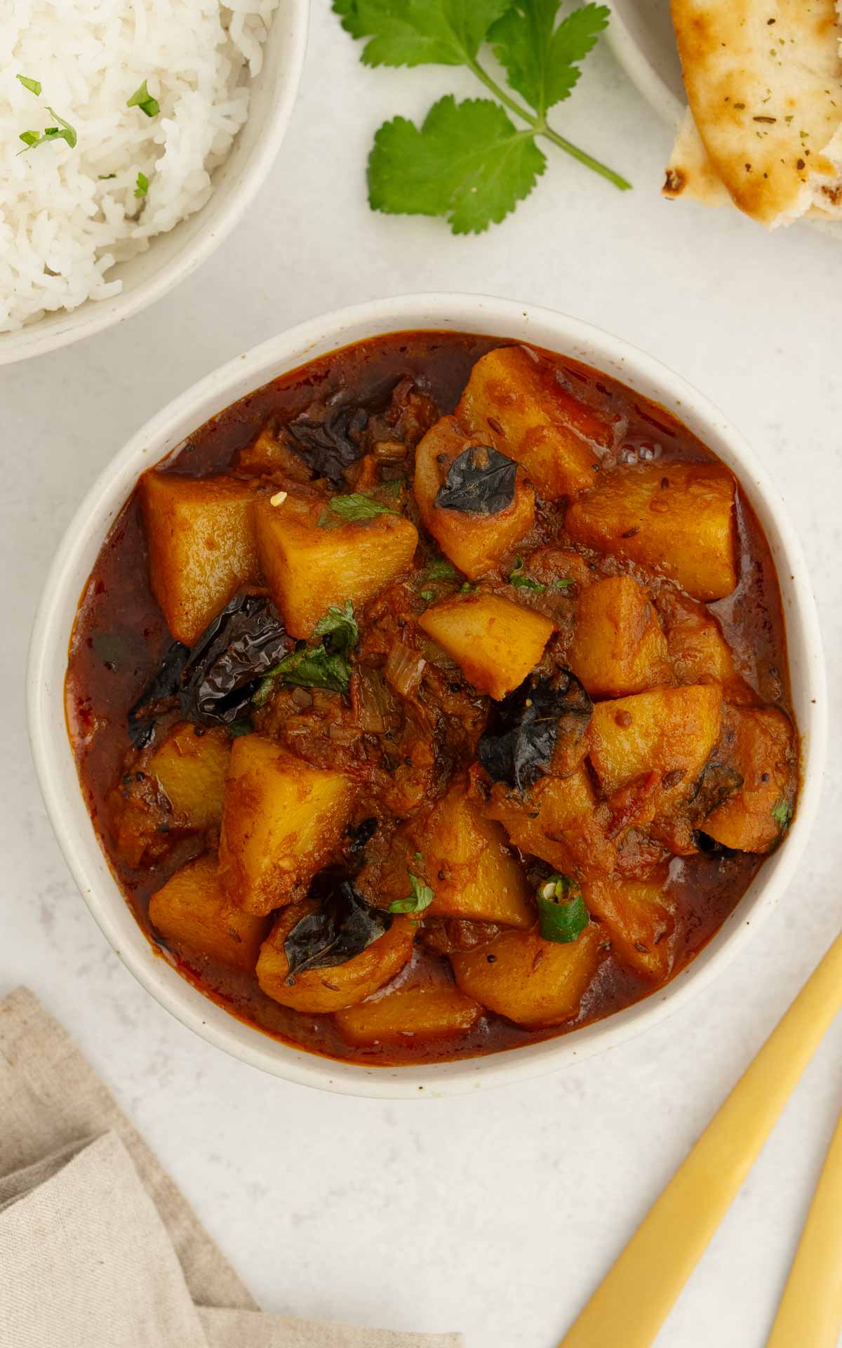A white bowl containing potato chunks with curry sauce. 