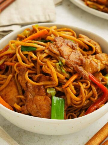 A white bowl containing chow mein with chicken.